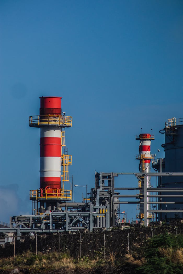 Vertical shot of industrial chimneys with red and white stripes under a clear blue sky.