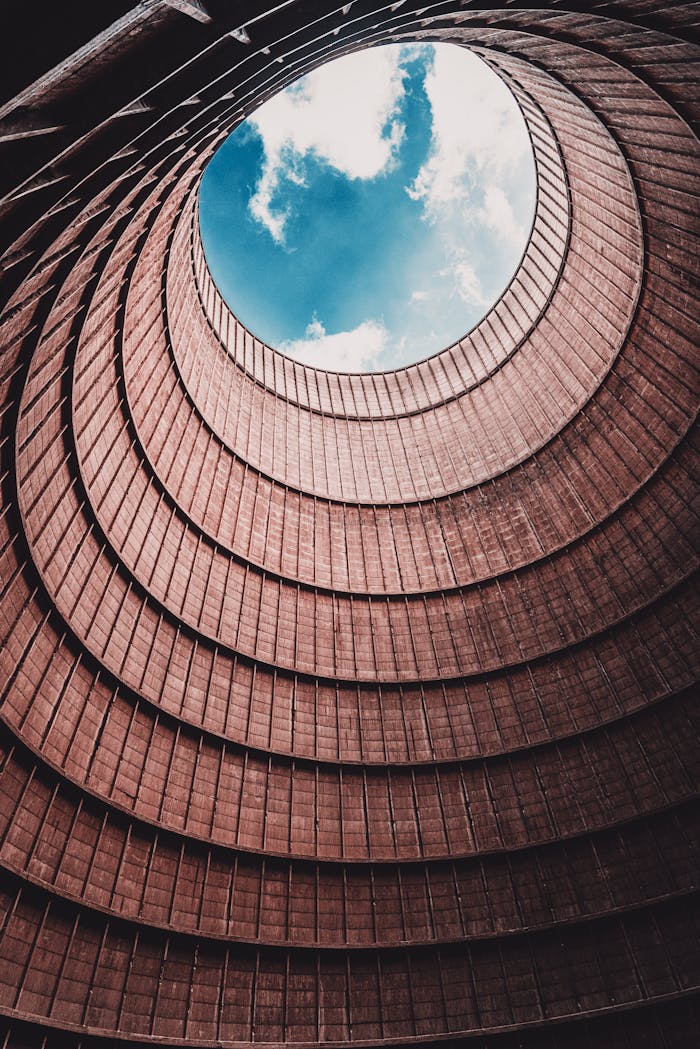 Dramatic interior view of a cooling tower with open sky above.