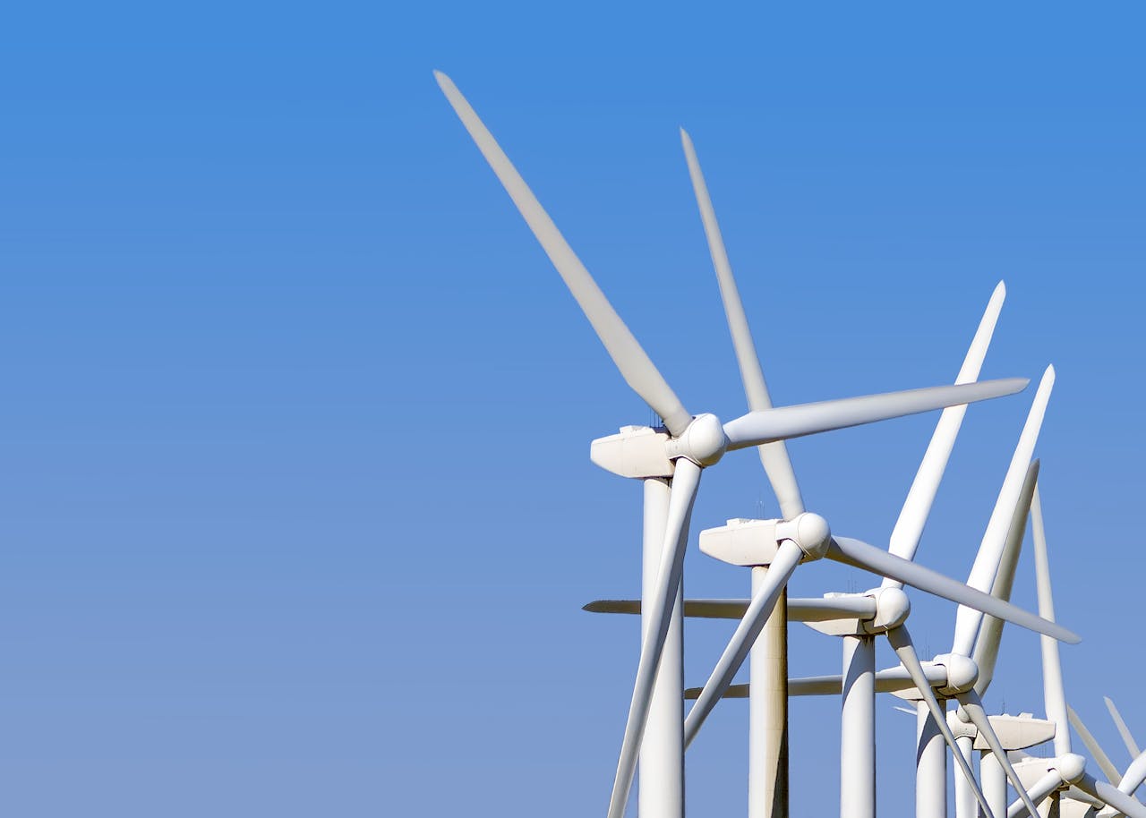 services-06 Wind turbines generating clean energy stand tall against a clear blue sky, highlighting sustainable technology.
