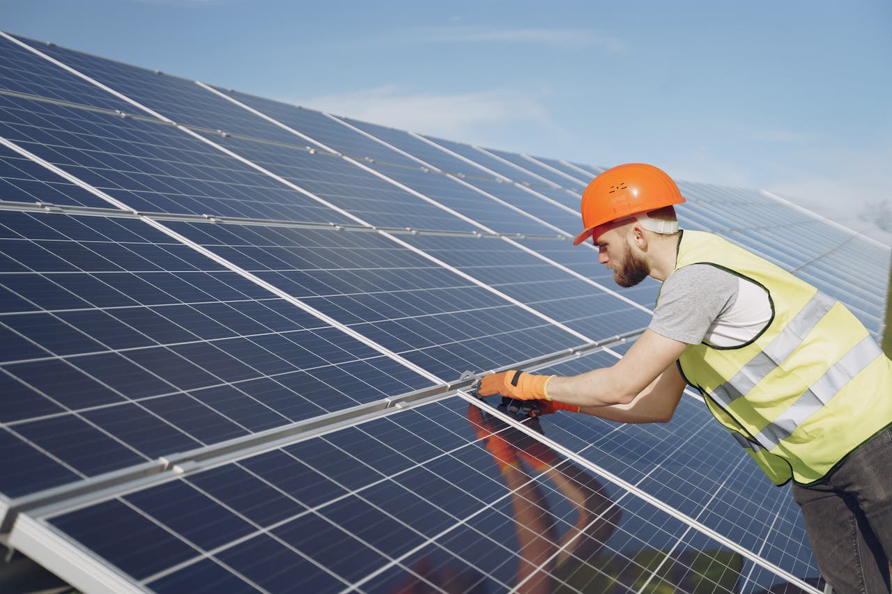 home-hero Side view of focused young man in uniform and hardhat checking setup of solar panels
